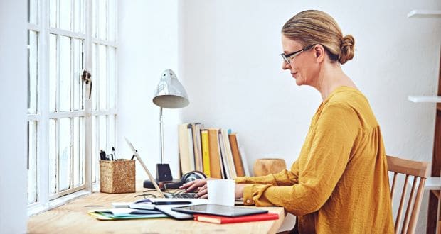 Woman sitting at laptop PC in home environment
