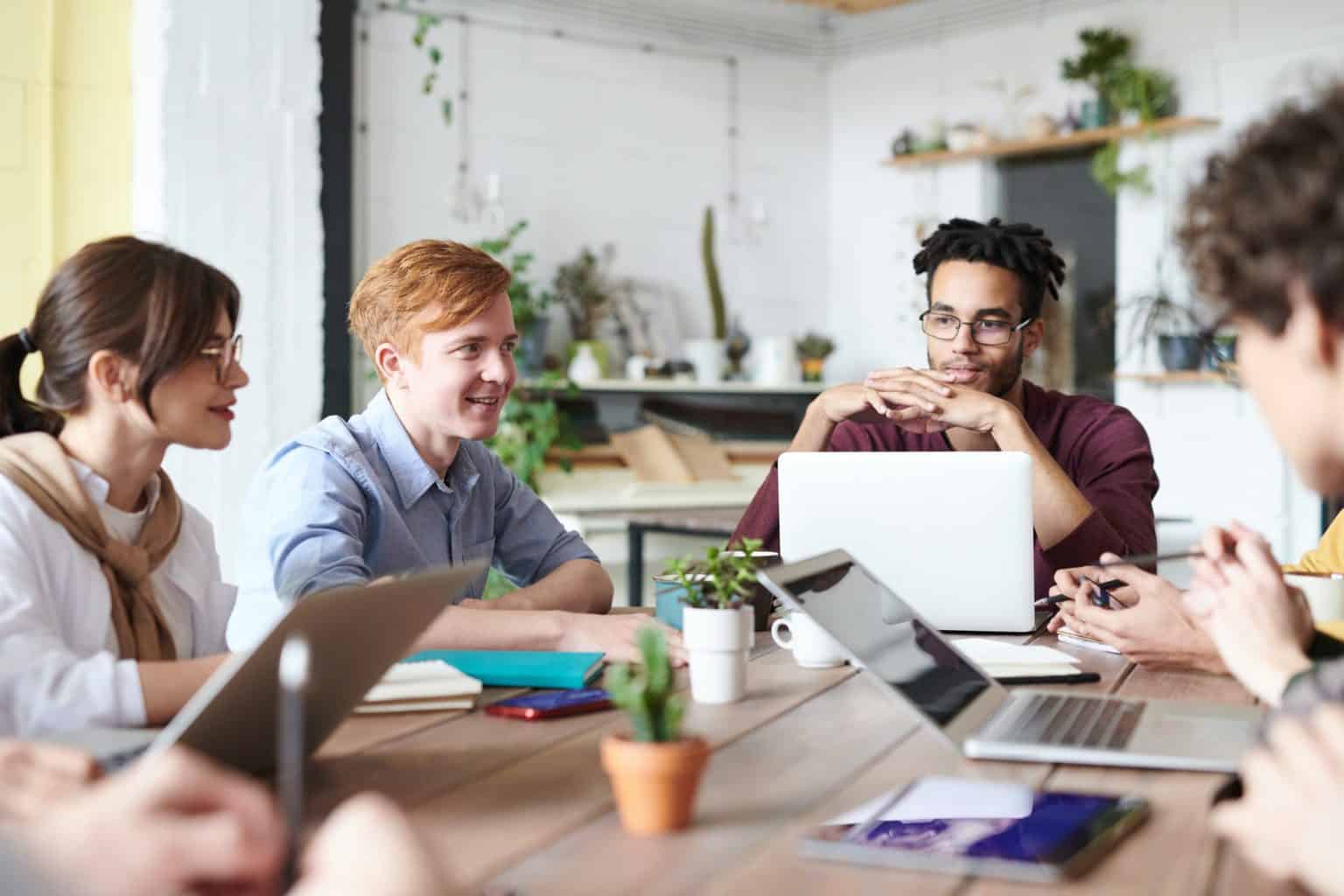 Mixed group of colleagues sit around a desk on laptops IT security