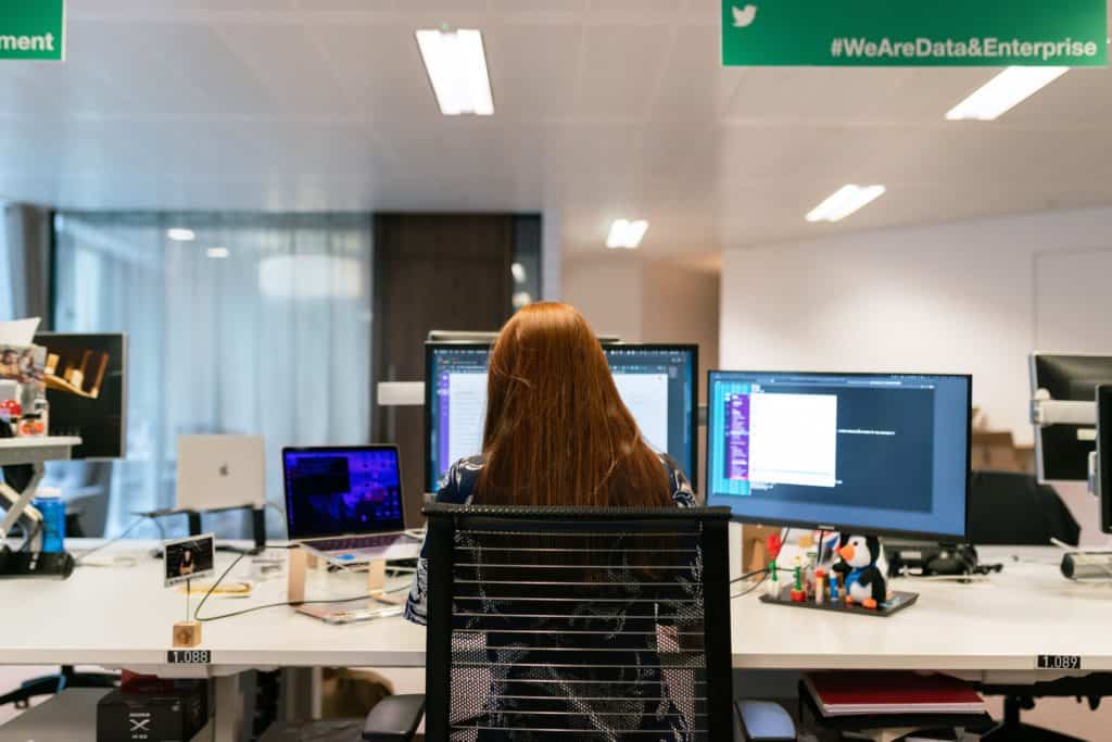 Red haired woman with her back to the camera working on a PC