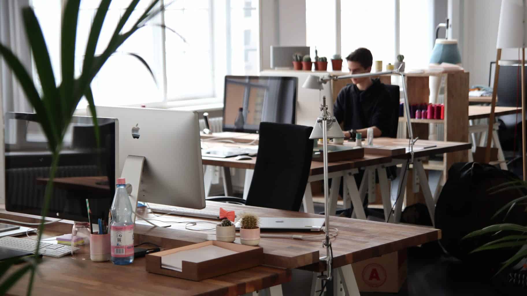 IT security office with lone man working at a desk and empty PC desk