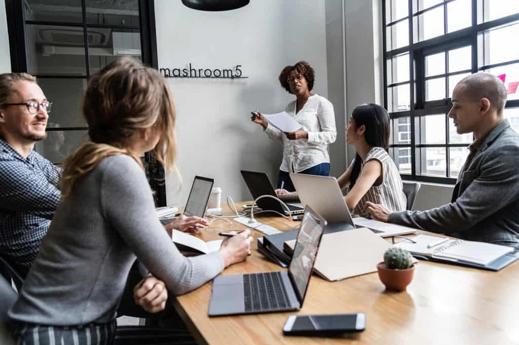 A group of people in a meeting with laptops