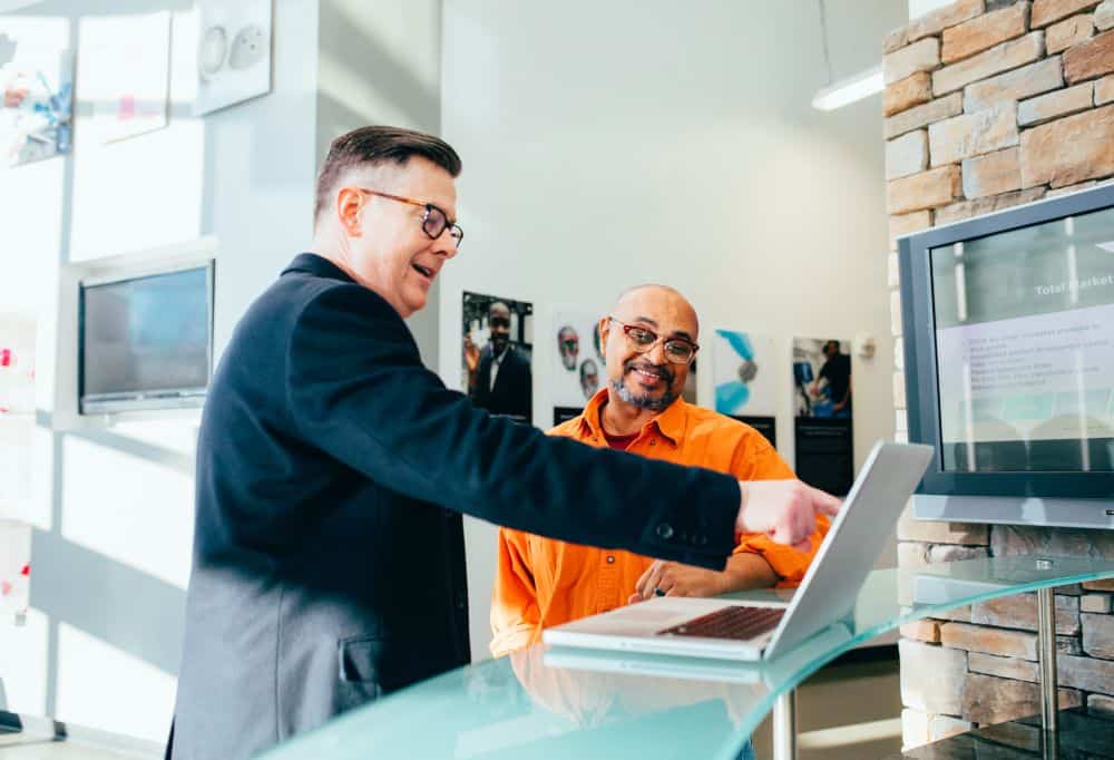 Two men in conversation on laptop in office