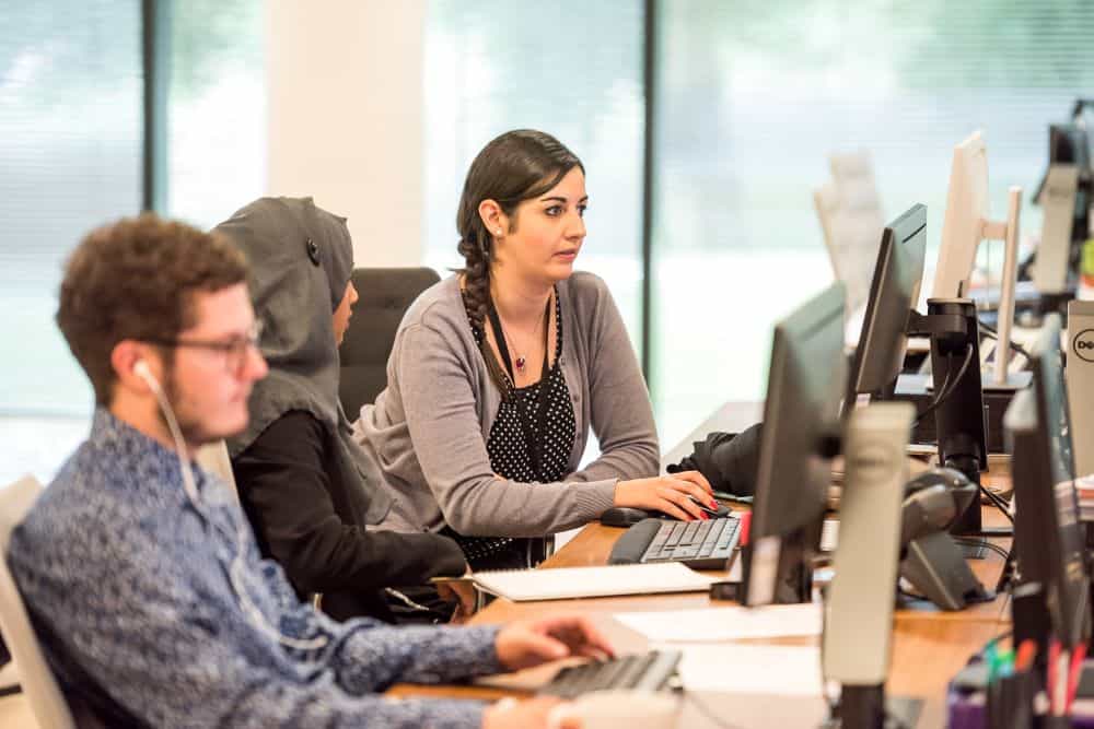 Workplace setting with two women and a man working on computers