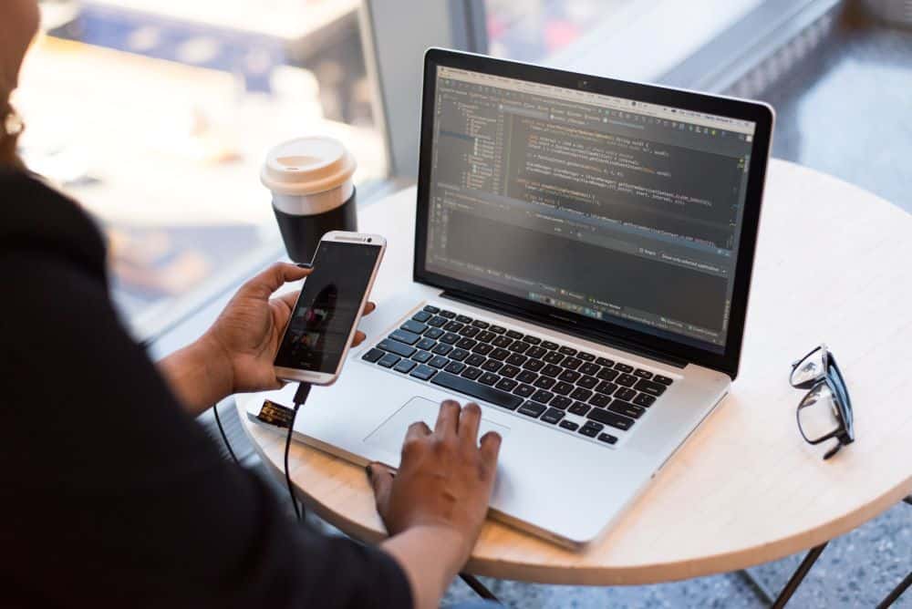 Person Working Remotely in Cafe with Laptop and Phone