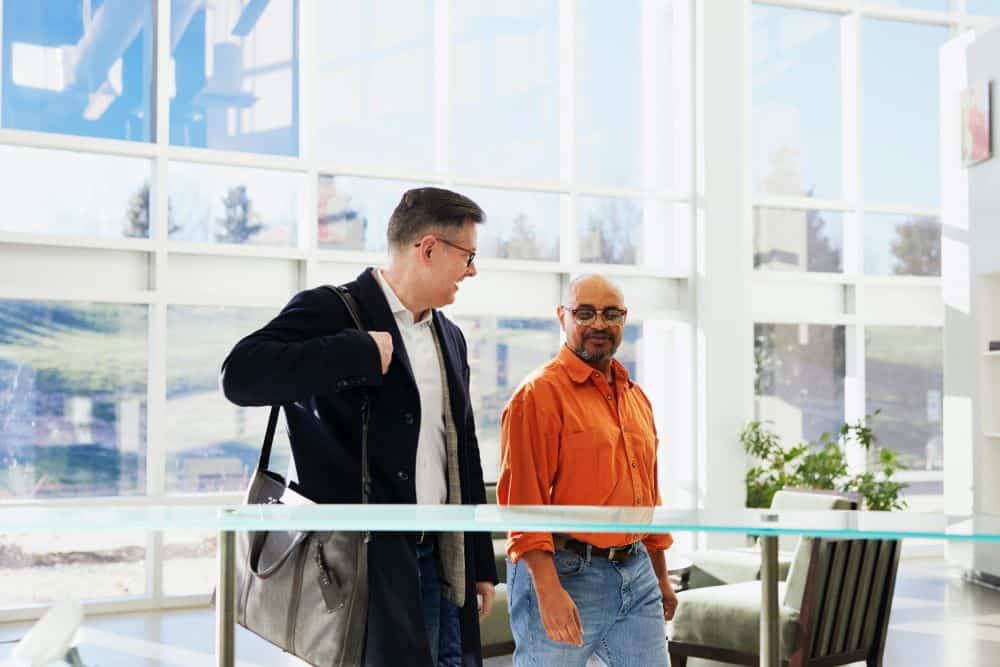 Two men in conversation walking through office