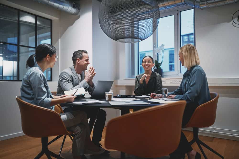 Group,Of,Diverse,Businesspeople,Laughing,Together,During,A,Meeting,Around