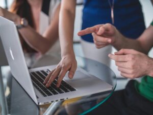 Person Helping Coworker at Laptop